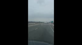 Smoke rolls across the interstate as an 18 wheeler that transports other vehicles, catches flame on the side of the road.