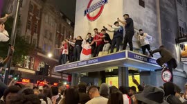 Celebrating fans climb on top of entrance of Leicester Square Station