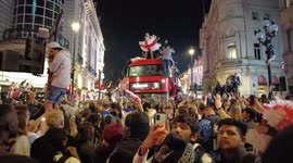 Fans climb double-decker bus in Piccadilly, London after England clinches Euro 2020 finals berth