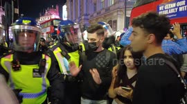 Police throw a mans mobile phone to the ground as he argues with them in Piccadilly London