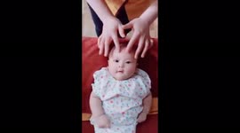 Cute expression of a 6-month-old girl when her mother massages her face