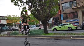 Man riding and dancing on 6 foot tall unicycle in Queens, NY