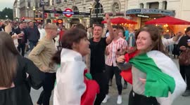 Let’s get the party started! Fans wrapped in St George and il Tricolore flags sing ‘Sweet Caroline’ in London’s Piccadilly Circus