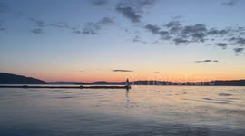 Long View with Pan of Lighthouse on Relaxing Waves at Sunset