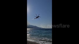 Helicopters scoop up water in efforts to extinguish wildfire on Samos