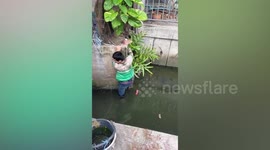 Motorcycle rider climbs into dirty canal to help stranded kitten