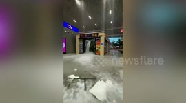 Rain pours into train station and floodwater bursts open shop's doors in central China