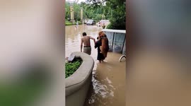 Chinese man carries pet golden retriever on back as he walks through flooded road