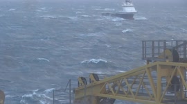 Offshore Supply Vessel Tossed Around by Meter High Waves In Front of an Oilrig in the North Sea