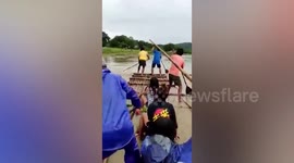 Residents cross submerged rice field using raft as Typhoon In-fa hits the Philippines