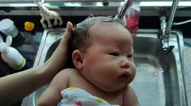 Adorable newborn baby gets hair washed by her mom