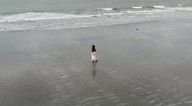 drone shot - woman walking alone along the beach in jericoacoara brazil