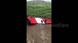 Lurin Valley activists hold the Peruvian flag against the backdrop of the mountain