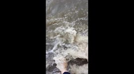 Commuters wade through muddy floodwater in London suburb