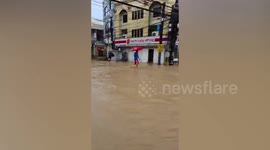 Residents walk across muddy floodwaters after heavy monsoon rains submerge village in the Philippines
