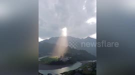 Sunlight beams through hole in thick clouds after rainfall in southern China