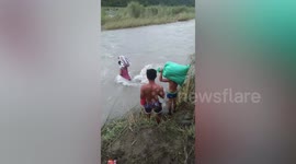 Teachers struggle to cross overflowing river to reach school in the Philippines during monsoon season