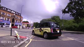 Impatient taxi driver over takes 2 cyclists and then turns left in front of them.