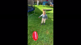 Little boy practicing kicking his aussie rules football