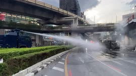 Water cannon puts out a vehicle fire at anti-government protests in Bangkok