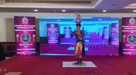 Folk artist dances barefoot on glass pieces while wearing heavy headgear in southern India