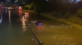 Cars drive through major flooded streets from heavy rain in Michigan