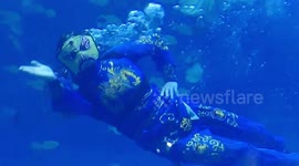 Chinese diver performs magic trick while swimming among fish at amusement park