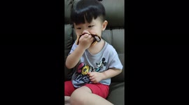 Messy toddler eating chocolate ice cream with mouth covered choco cream