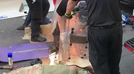 Police work to free the arms of two Extinction Rebellion protesters who have cemented their arms into a metal pipe