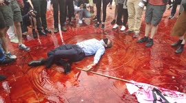Extinction Rebellion protester performs bizarre stunt, writhing around in fake blood and screaming, 'Money!'