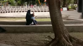 Mom Wearing Burqa Comb the Hair of Her Daughter in Public Garden