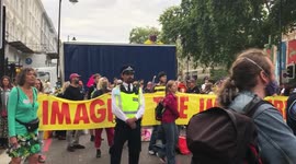 Extinction Rebellion protesters play drums after blocking road in London, with one protester on top of a lorry