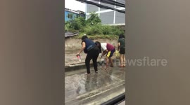 Locals catch fish on flooded road after heavy rain in Thailand