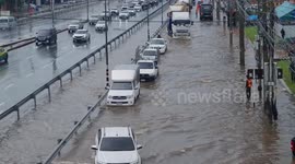 Cars drive through flooded road after heavy rain in northern Thailand