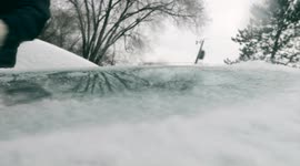 Close-Up View of Person Removing ice covered with snow From His/Her Car