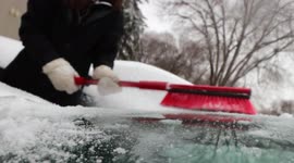 Close-Up View of Person Removing ice covered with snow From His/Her Car