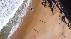Drone footage of two lovers walking along the beach who kiss