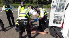 Police remove jewellery from an arrested protester and place her in to the back of a carrier after they had been locked to other protesters on a car on the A1020 blocking access to ExCeL London