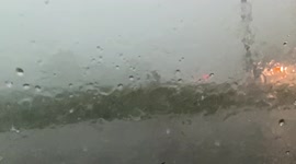 HAIL falling in slow motion while passing pickup truck through rainy intersection