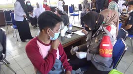 Indonesian police officers vaccinate students so they can return to schools. Death rate in under-18s is more than three times world average