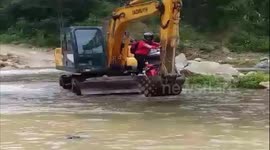 Digger transports residents through deep floodwater due to heavy rain brought by tropical storm Conson