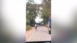 Biker carrying long stick slows down traffic in Thailand