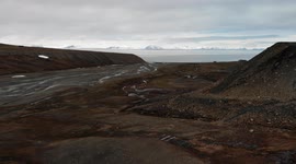 Svalbard (Spitsbergen) drone view. Glacier in spring, huts and homes in the background. Sea and mountains view near Longyearbyen