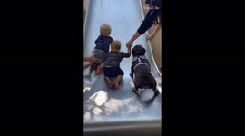 Excitable French bulldog shows kids at park how to go down the slide