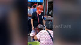 Woman wears plastic bag on her head as new COVID-19 cases emerge in southern China