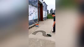 Chinese man uses wet mop to draw detailed dragon on dusty ground