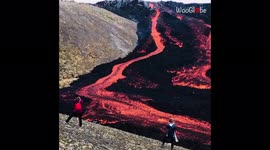 Tourists in awe of magnificent lava flowing from volcano in Iceland