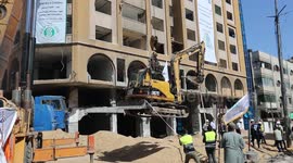 Palestinian workers remove rubbles of al-Jawhara tower hit by Israeli strikes during last attack on Gaza