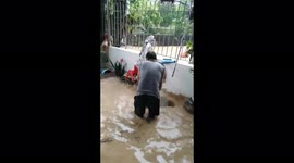 Desperate man attempts to push away floodwater inside his house following tropical storm