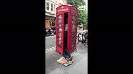 Drunk man sleeping in iconic London red phone box